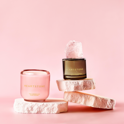 The 3.4 fl oz HeartStone Eau de Parfum and 6.5 oz Scented Candle showcased on a three-tiered stone tower.