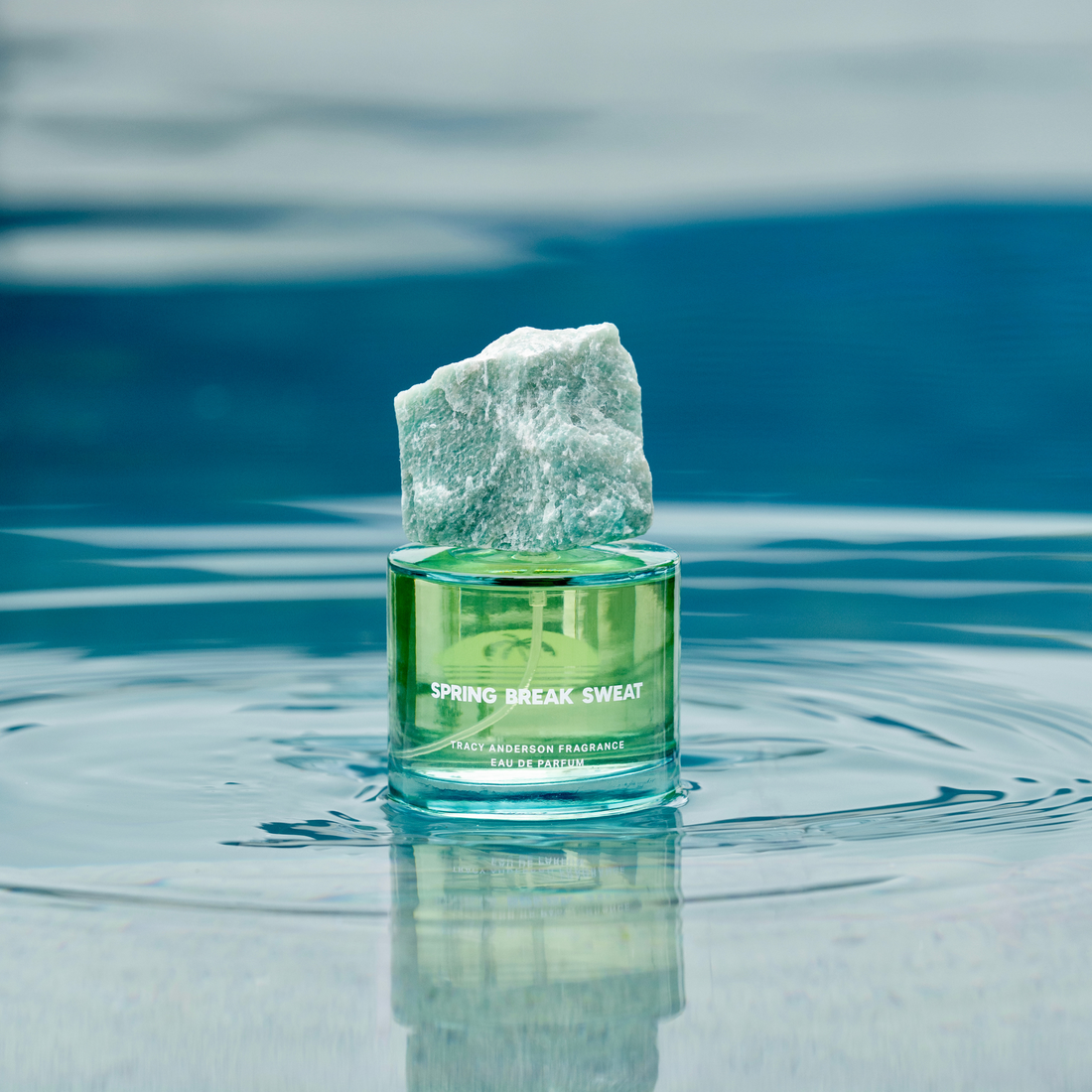 The Tracy Anderson Spring Break Sweat fragrance resting in a shimmering pool of water.